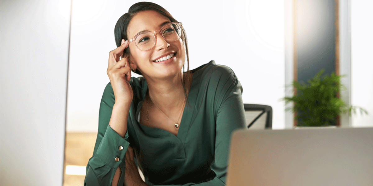 Happy young smiling businesswoman sitting in front of her laptop.